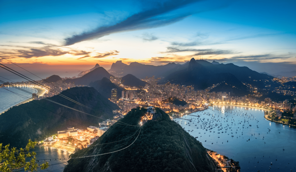 Night aerial view from the top of Sugarloaf Mountain in Rio de Janeiro, highlighting the illuminated cityscape.